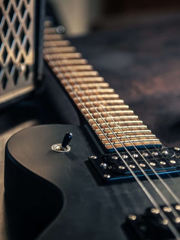 Close-up, black electric guitar on a dark background, the concept of musical creativity, modern musical instruments.